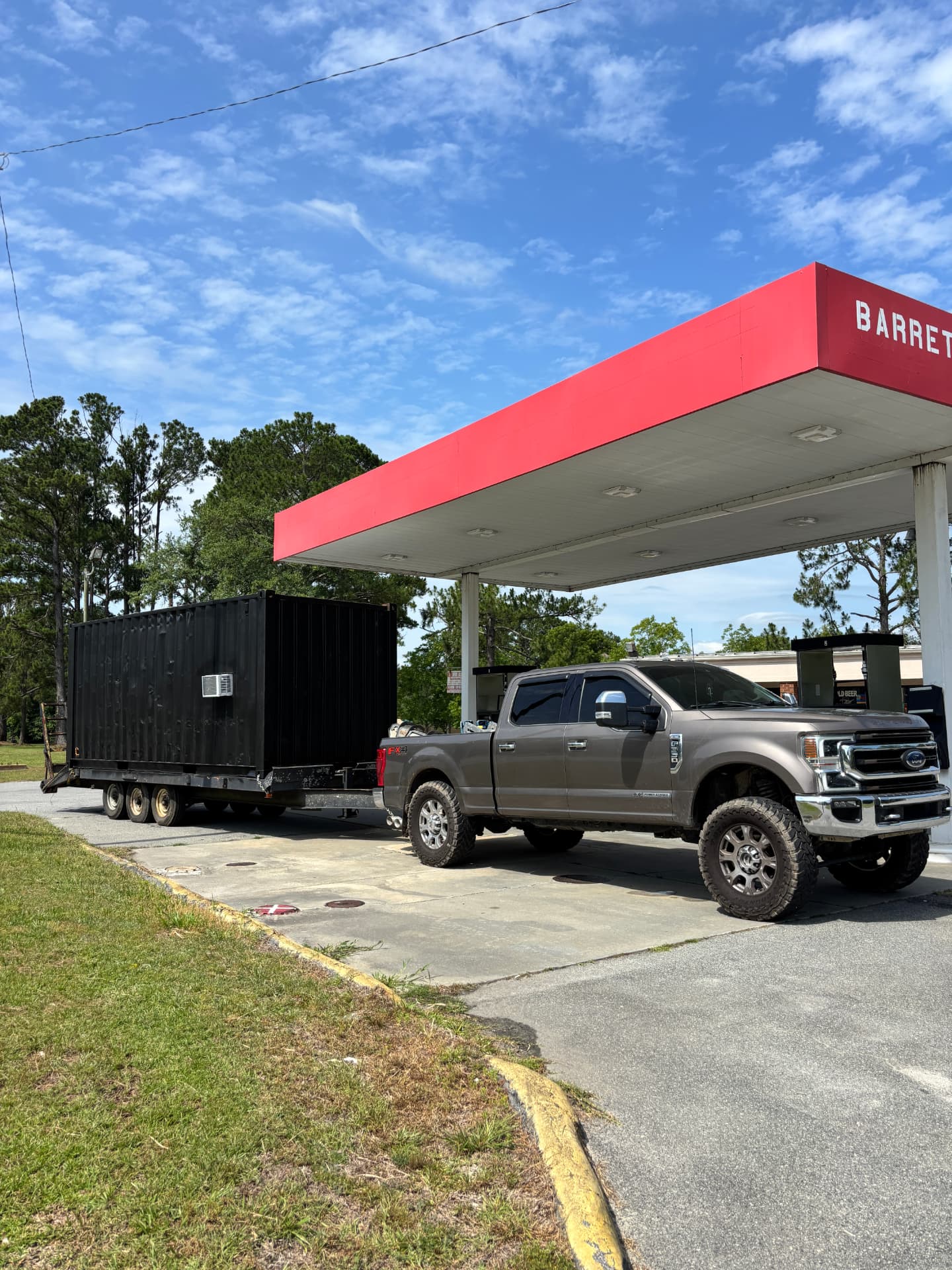 Pickup and flatbed trailer hauling a modified shipping container