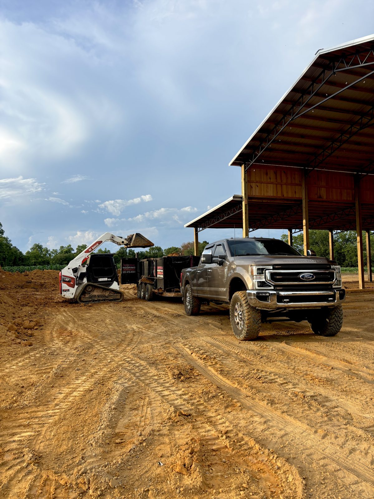 Skid steer loading a dump trailer on a dirt job site